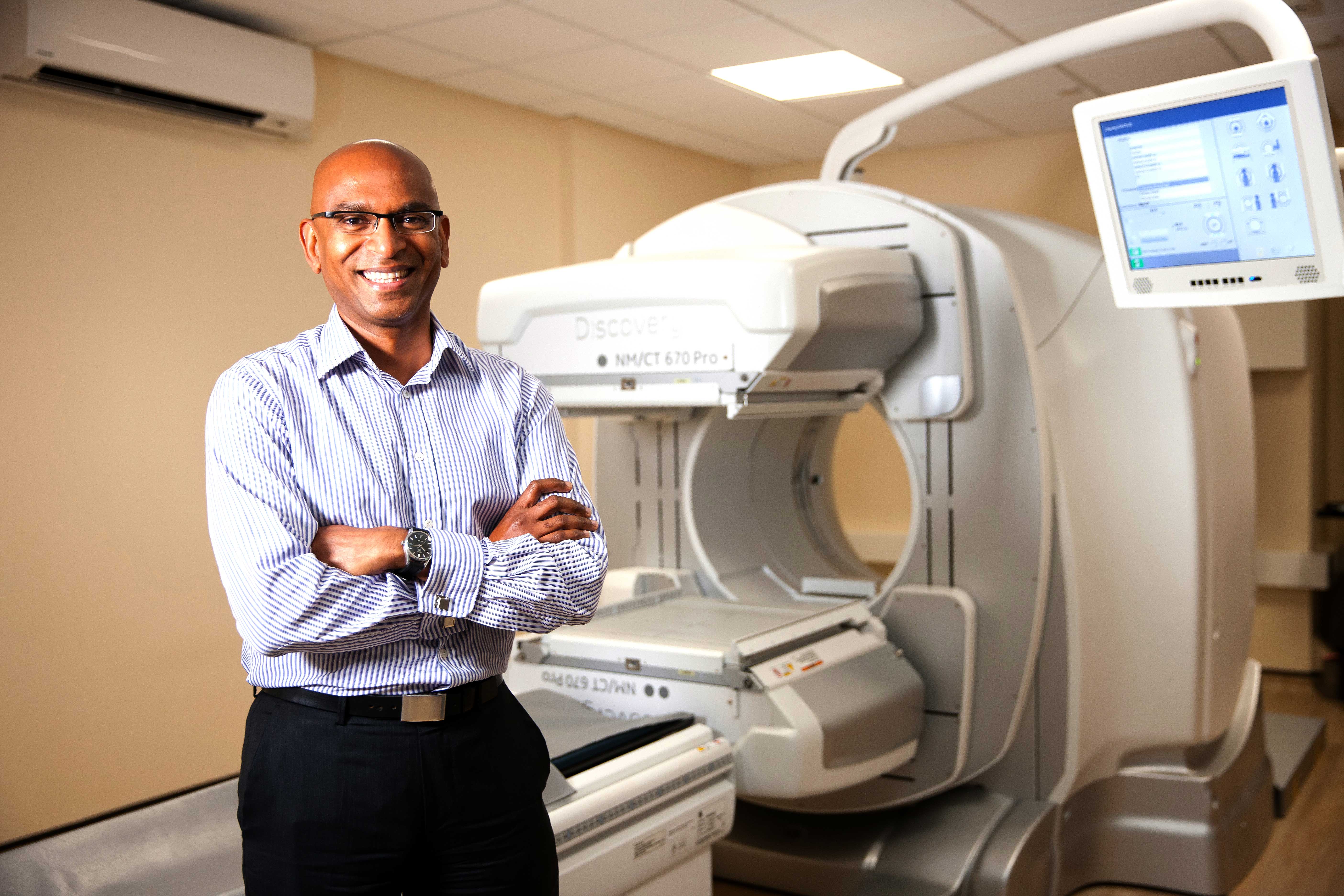 Dr Prakash Manoharan standing in front of a scanner.